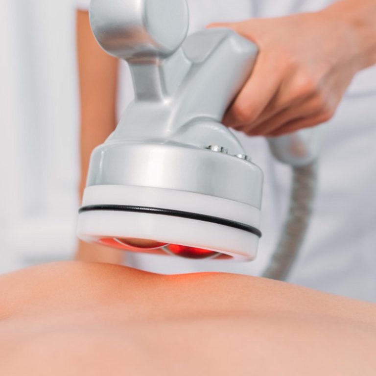 cropped shot of woman on massage table getting electrical massage done by cosmetologist in spa salon